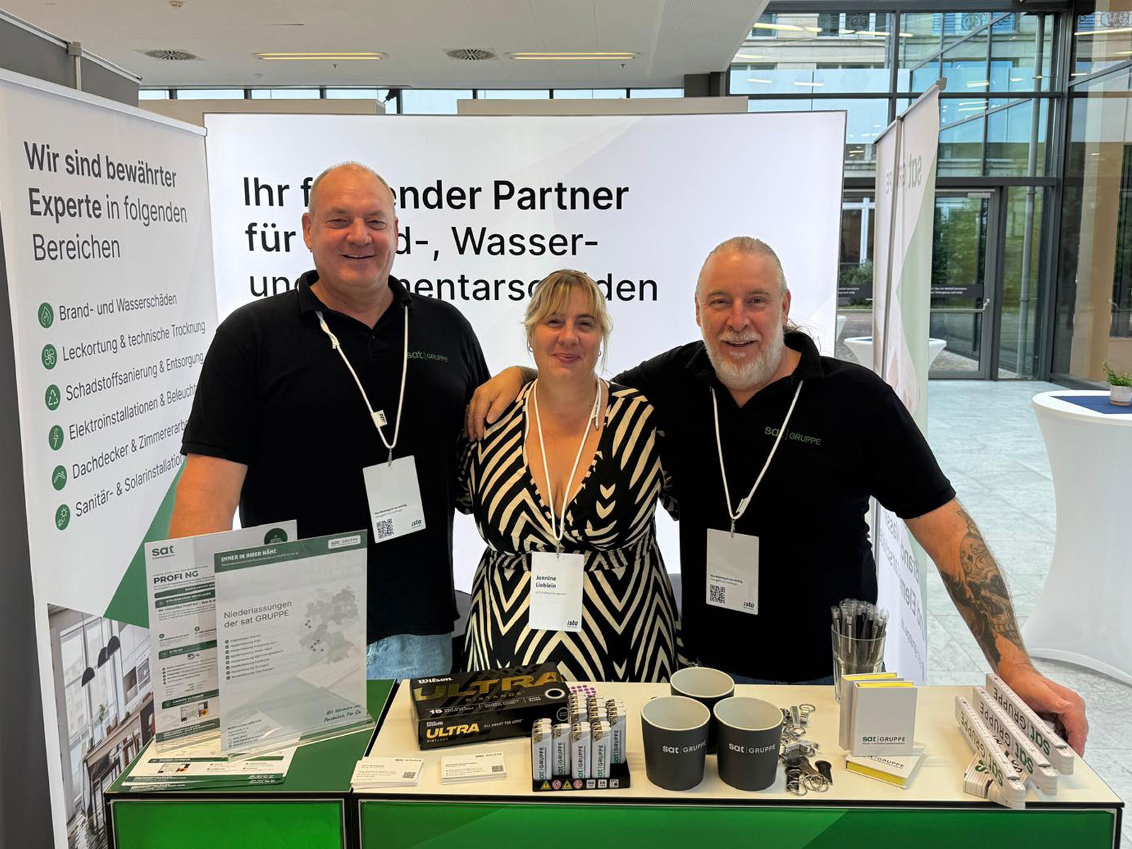 3 Mitarbeitende von vor dem Messestand der sat GRUPPE bei den ista Verwaltertagen